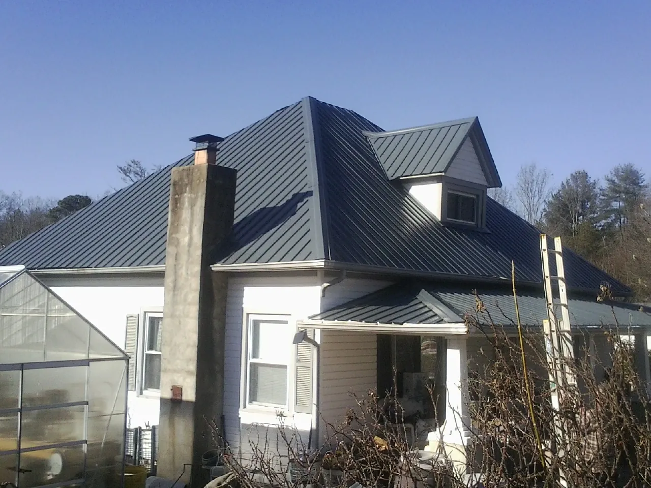 Dark blue standing seam metal roof on a white farmhouse with dormer — Slate & Tile Roof Repair by Roofing Brothers in Seabeck