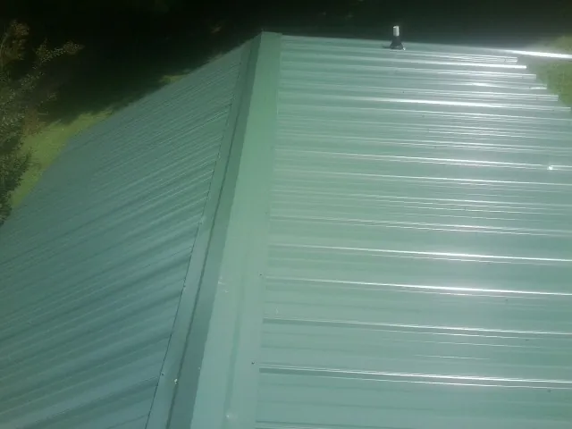 New green metal panels meeting at the ridge of a roof — Flat Roof Repair work by our crew in Seabeck