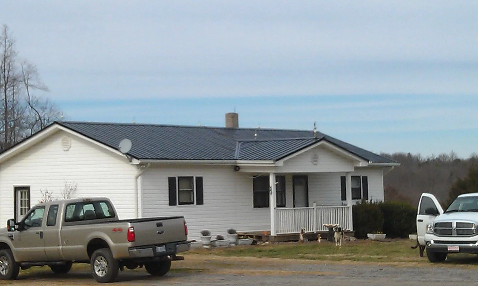 Finished dark metal roof on a white ranch home with work trucks parked in Seabeck