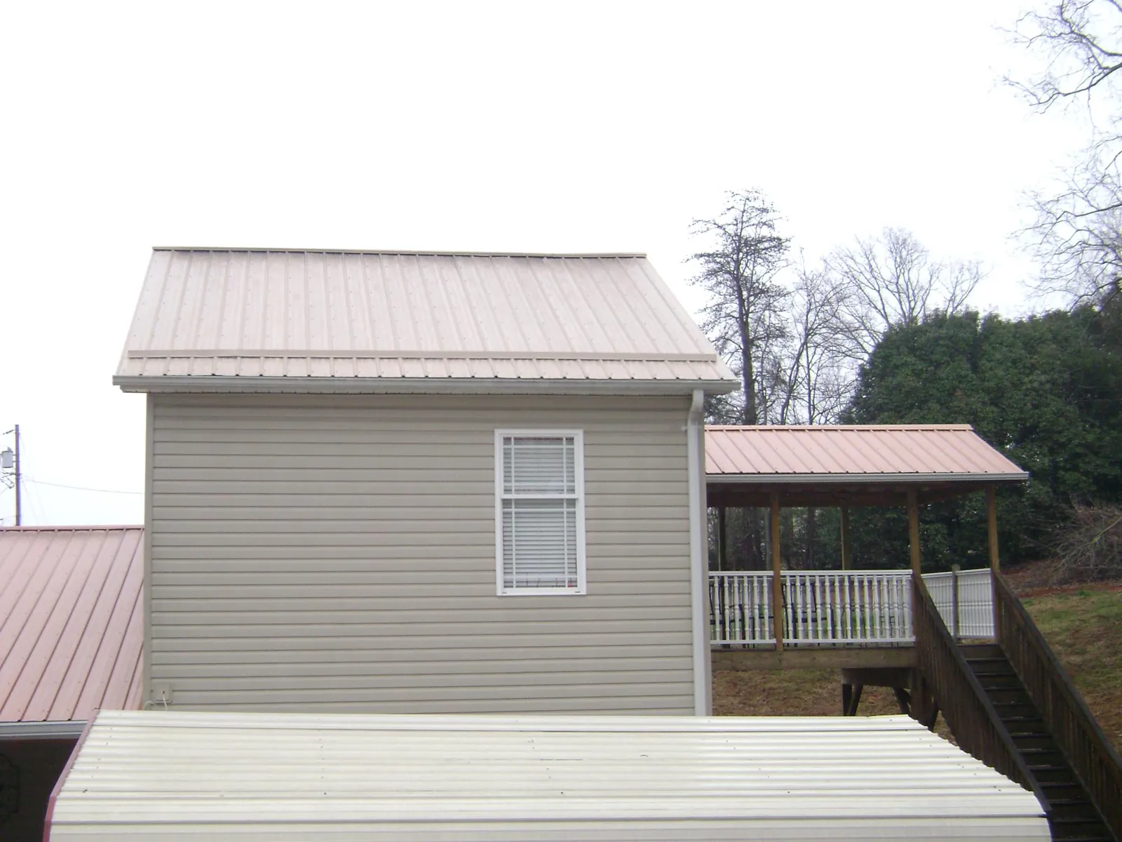 Tan metal roofs on a two story addition and attached porch, from a Roof Replacement job in Seabeck